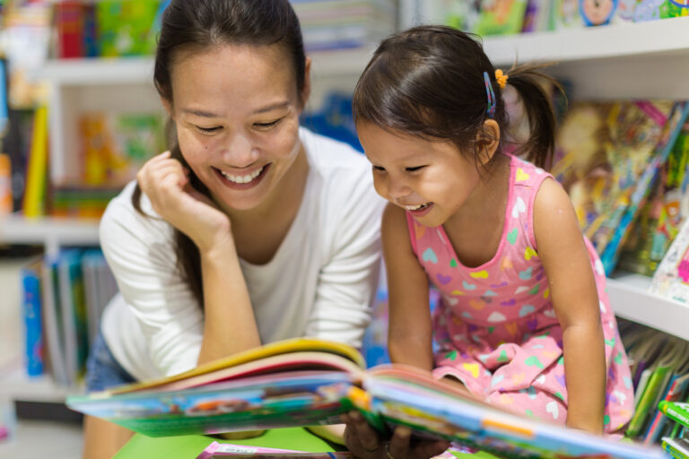 Parent and child reading books together in the library.